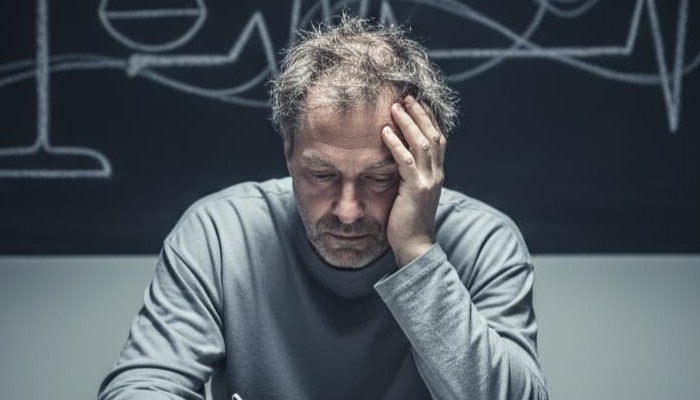 Man sitting down looking exhausted from mental torment
